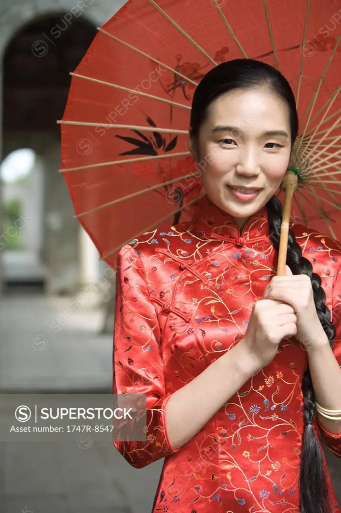 Young woman dressed in traditional Chinese clothing, standing under parasol, portrait