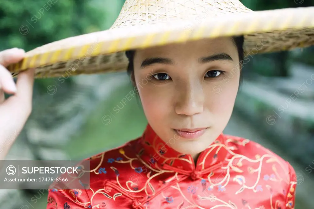 Young woman dressed in traditional Chinese clothing, holding edge of hat