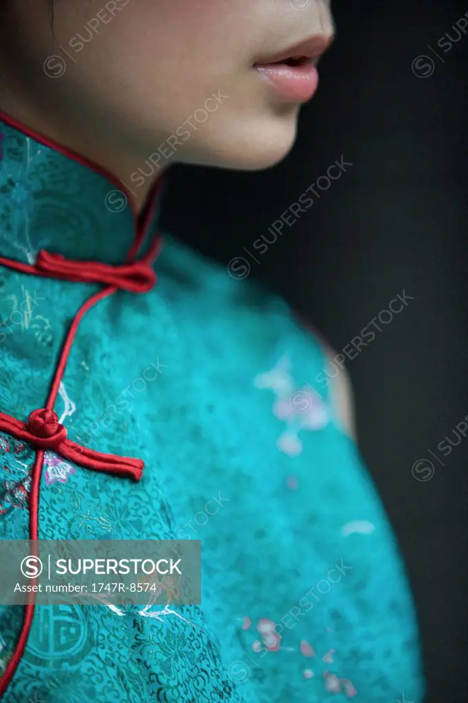 Young woman dressed in traditional Chinese clothing, cropped view of lower face and bust