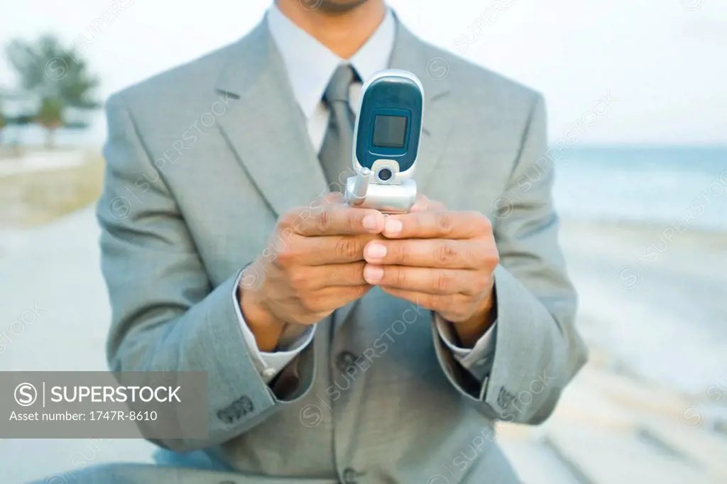 Businessman using cell phone outdoors, cropped view
