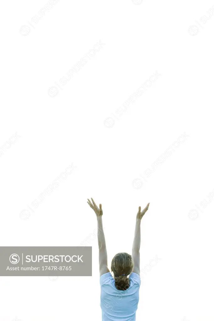 Teenage girl with arms raised, rear view