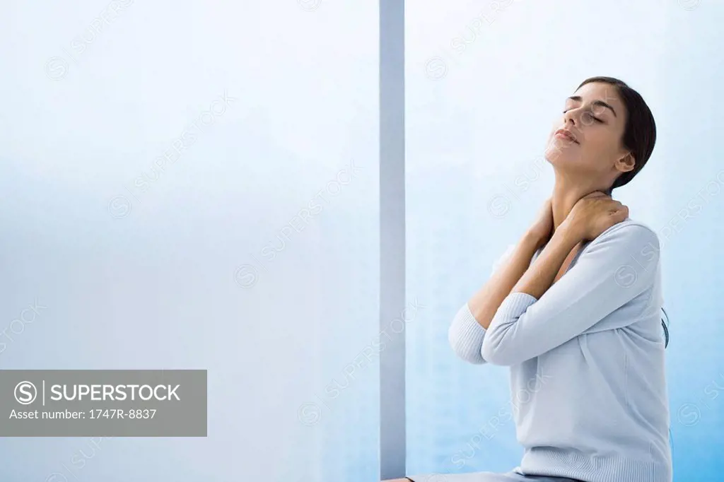 Woman relaxing with hands behind neck, head back and eyes closed, waist up