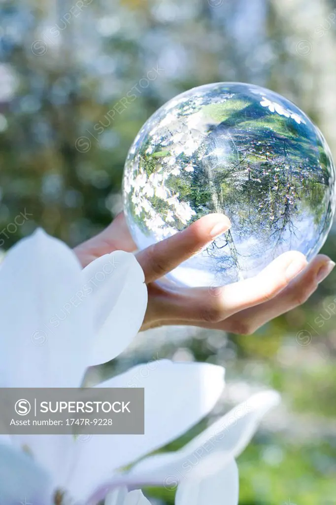 Woman holding glass sphere in hand, cropped view