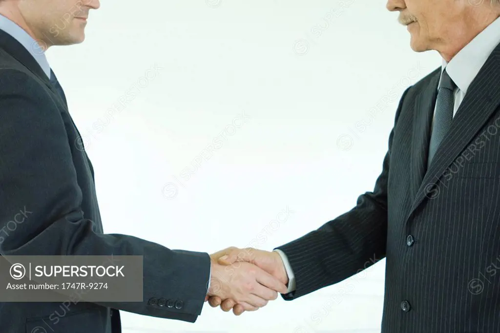 Two businessmen shaking hands, cropped side view
