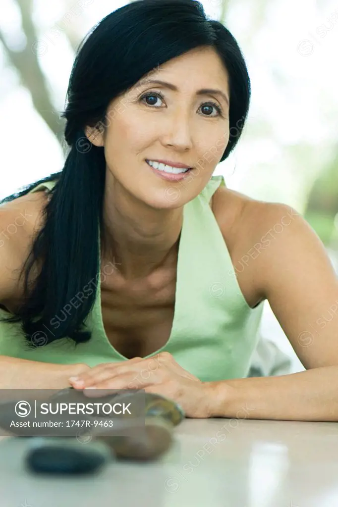 Mature woman smiling at camera, smooth pebbles in foreground