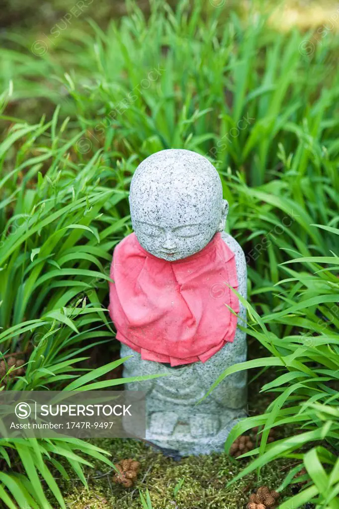 Devotional statuette in grass, close-up