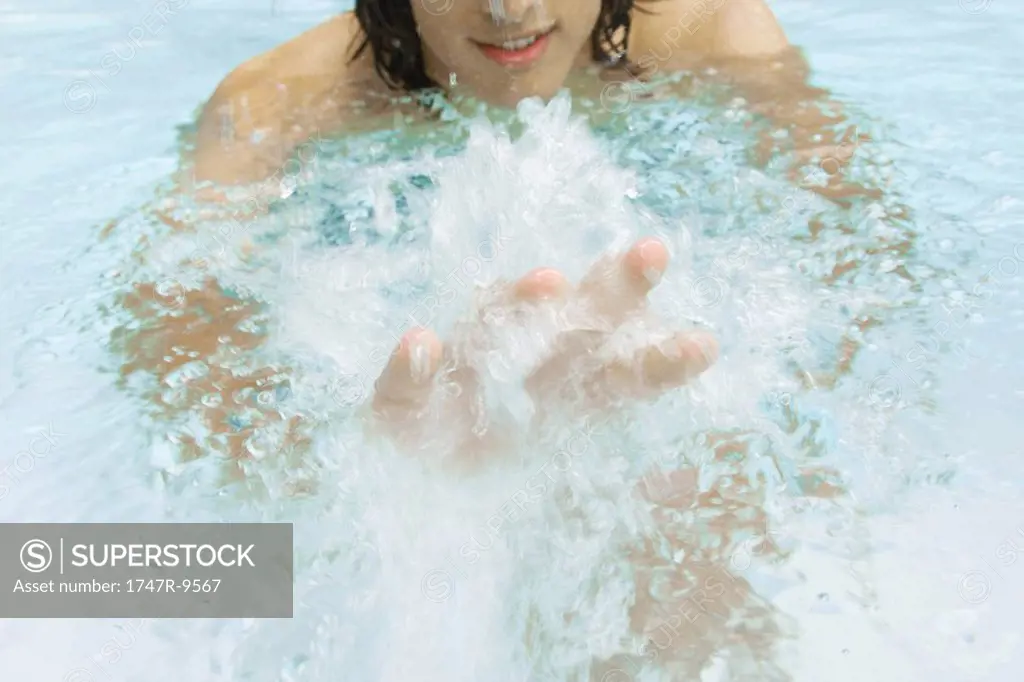 Man splashing in swimming pool, cropped view