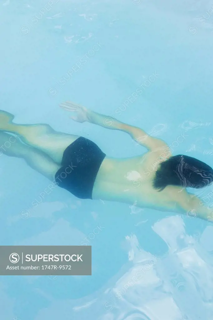 Man swimming underwater in swimming pool, high angle view