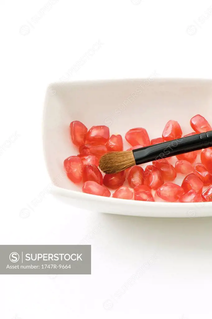 Fresh pomegranate seeds and make-up brush