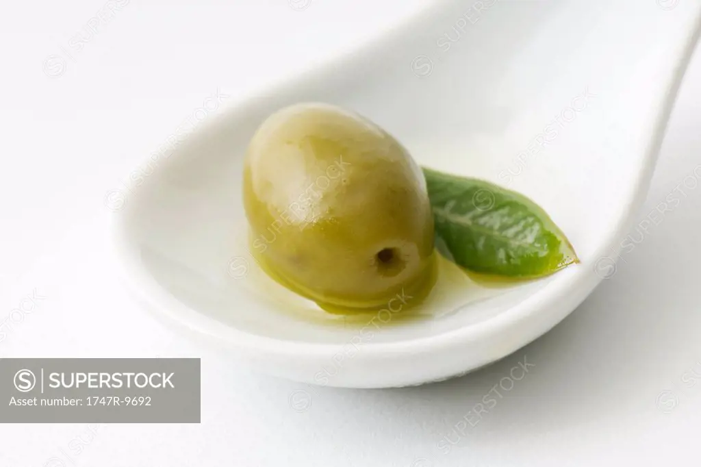Green olive in spoon