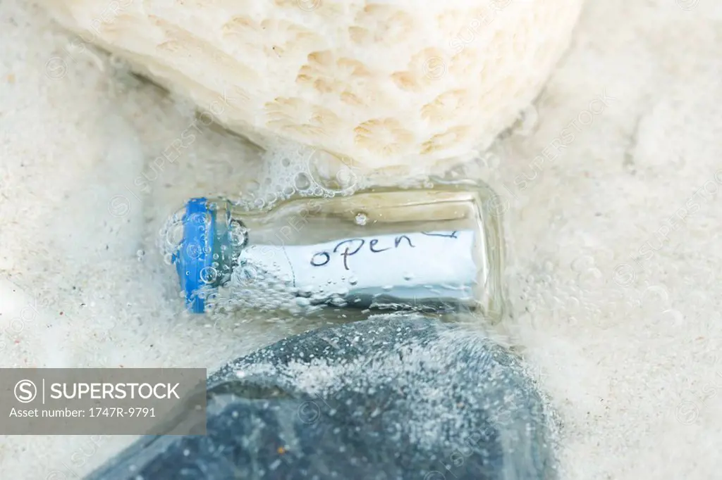 Bottle containing message in shallow water, close-up