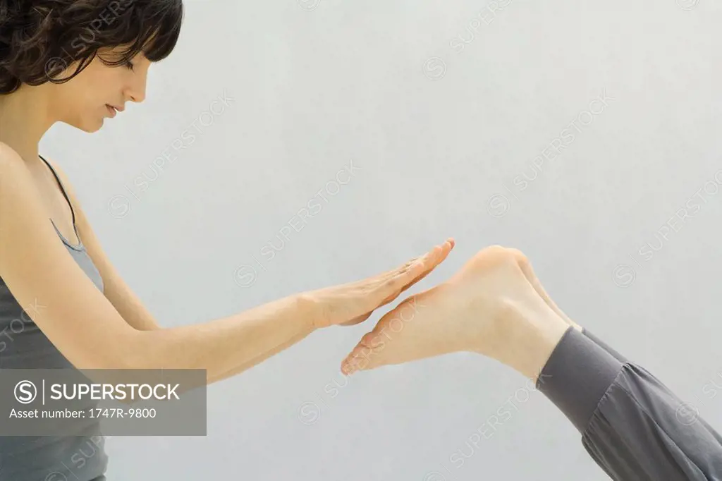 Woman performing reiki massage on person´s feet, side view