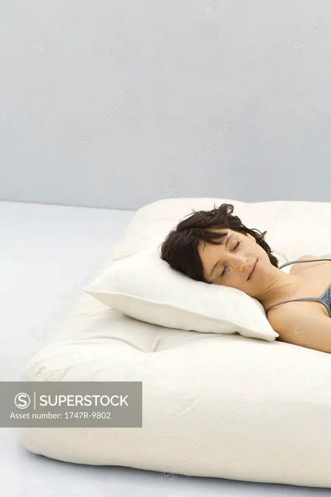 Woman lying on futon, eyes closed