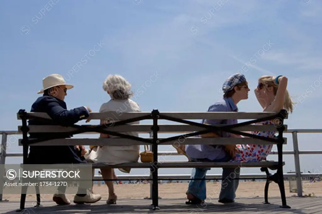 Young couple and a senior couple sitting on a bench