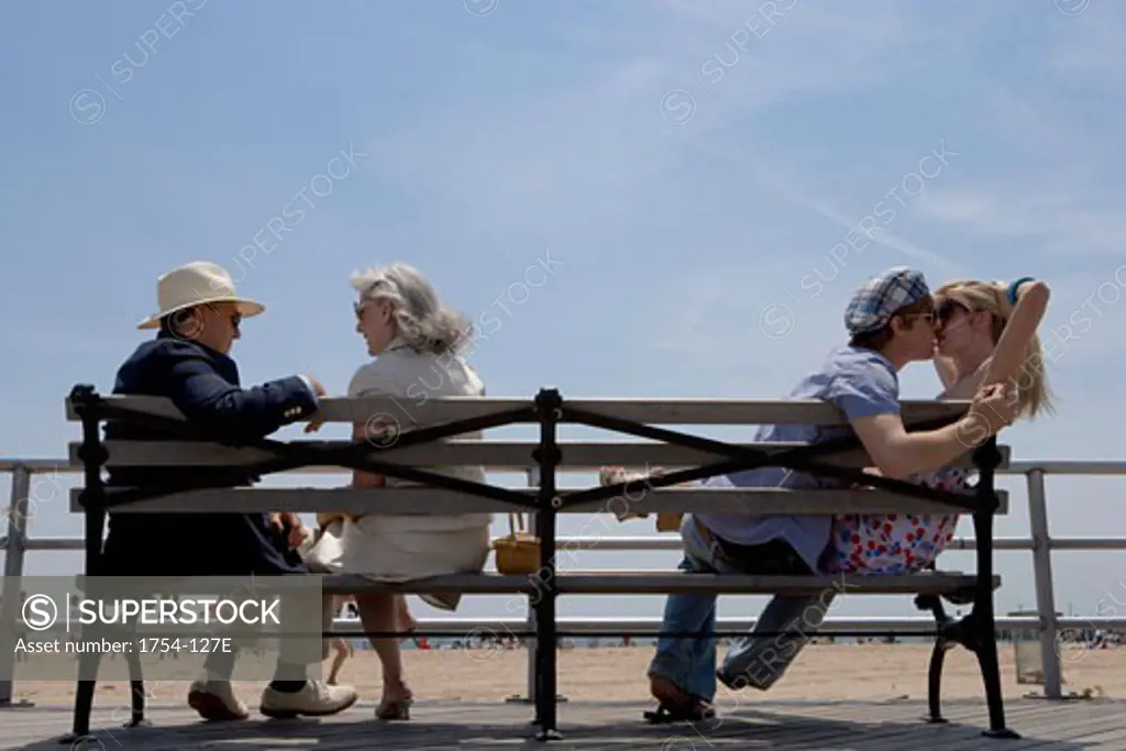 Young couple and a senior couple sitting on a bench