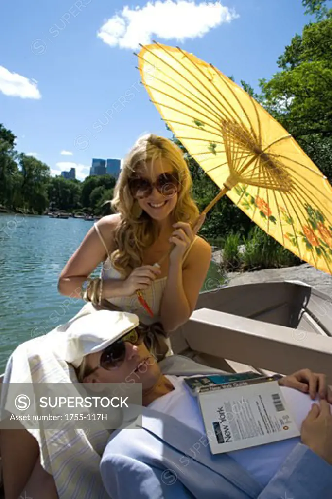 Young woman sitting in a boat smiling with a young man resting on her lap
