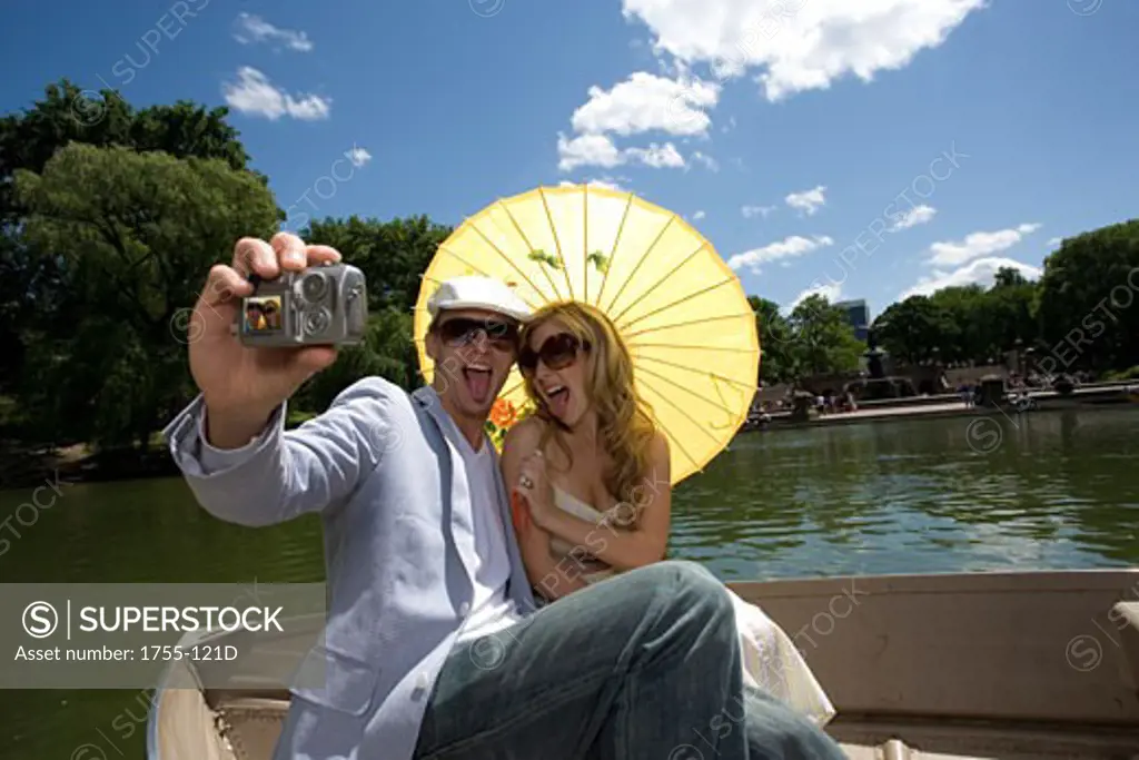 Young couple sitting in a boat and taking a picture of themselves, Central Park, Manhattan, New York City, New York, USA
