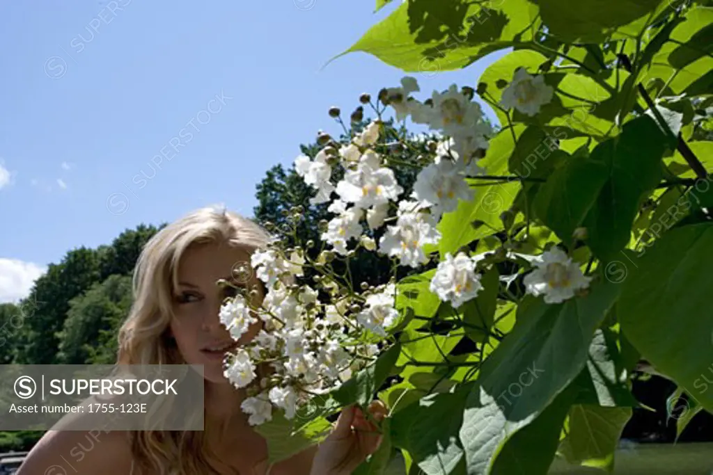 Young woman smelling flowers, Central Park, Manhattan, New York City, New York, USA