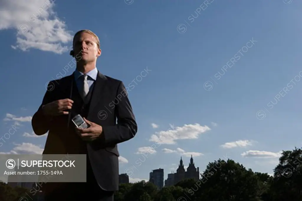 Low angle view of a businessman holding a mobile phone, New York City, New York, USA