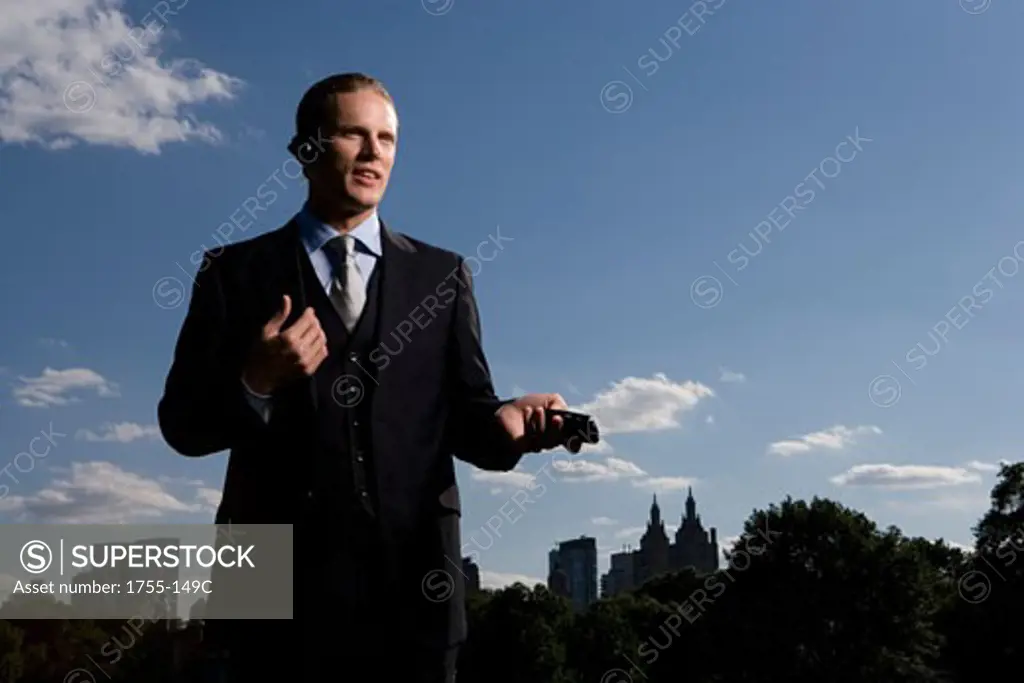 Low angle view of a businessman holding a mobile phone and smiling, New York City, New York, USA