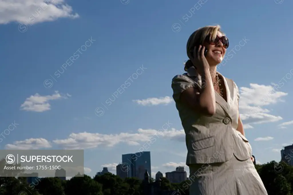 Low angle view of a young woman talking on a mobile phone and smiling, New York City, New York, USA
