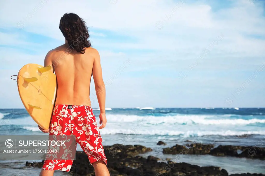 Hawaii, Oahu, young man at the beach with surfboard.