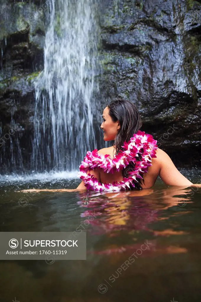 Hawaii, Oahu, Manoa Falls, Beautiful female with orchids leis sitting in a pond at the bottom of Manoa Waterfalls.