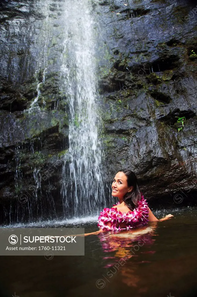 Hawaii, Oahu, Manoa Falls, Beautiful female with orchids leis sitting in a pond at the bottom of Manoa Waterfalls.