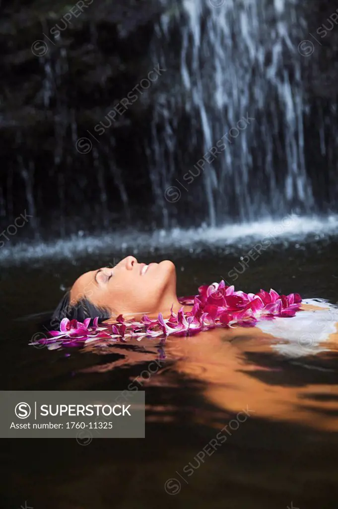 Hawaii, Oahu, Manoa Falls, Beautiful female with orchids leis floating at the bottom of Manoa Waterfalls.
