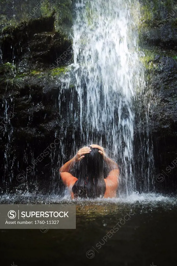 Hawaii, Oahu, Manoa Falls, Beautiful female sitting in a pond at the bottom of Manoa Waterfalls.