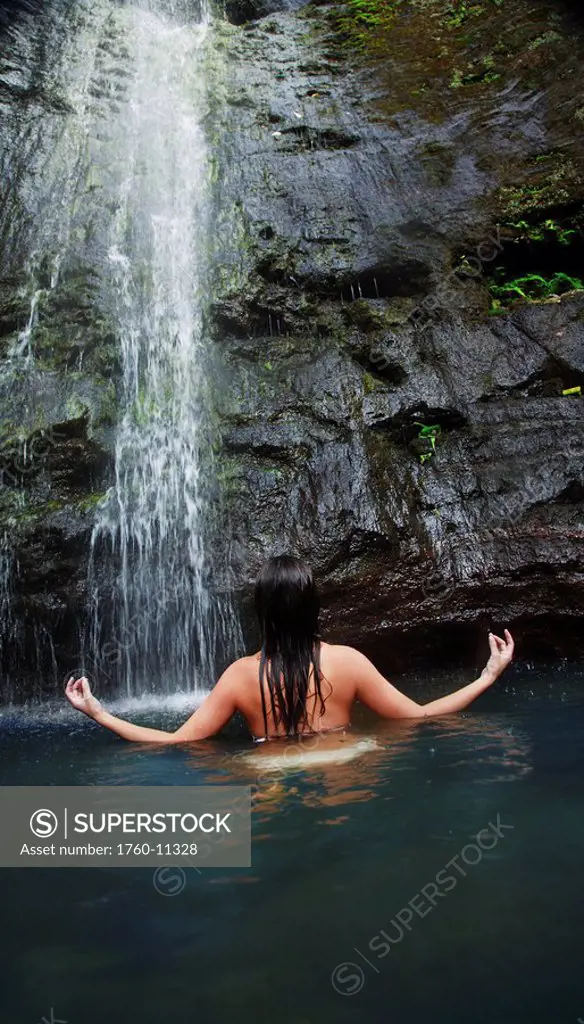 Hawaii, Oahu, Manoa Falls, Beautiful female sitting in a pond at the bottom of Manoa Waterfalls meditating.