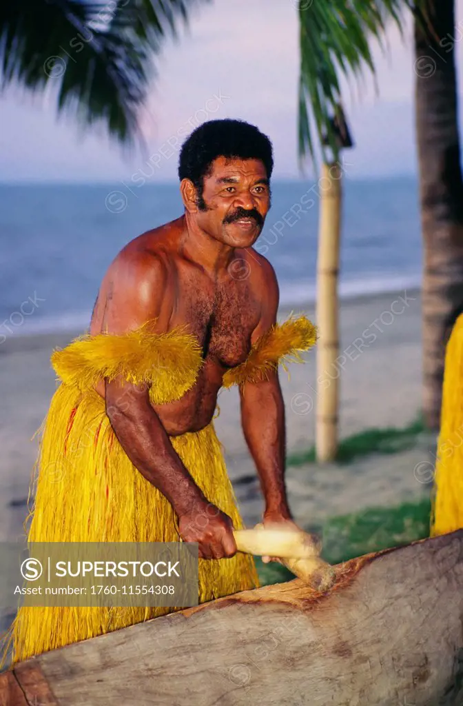 Fiji, Local Man In Grass Skirt Hitting Sticks.