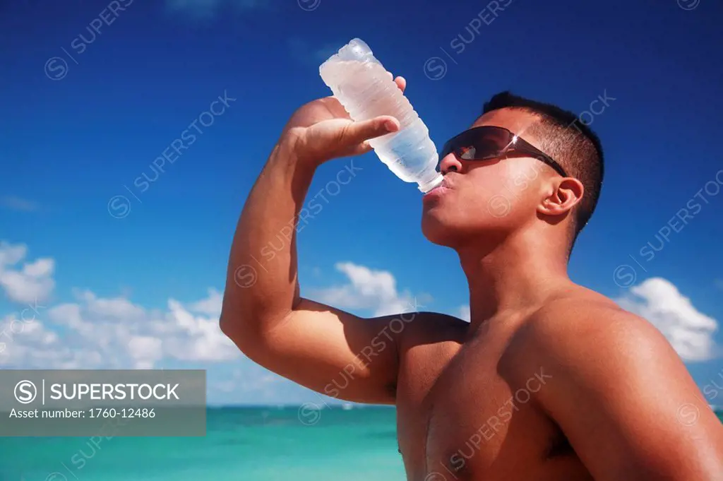Hawaii, Oahu, Fit male drinking water at the beach.