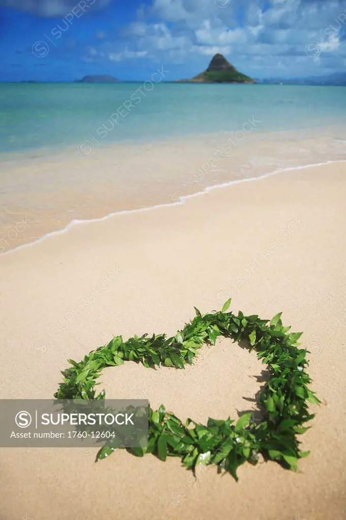 Hawaii, Oahu, Kualoa, Heart shaped Maile Lei on the beach with Chinamans Hat in background