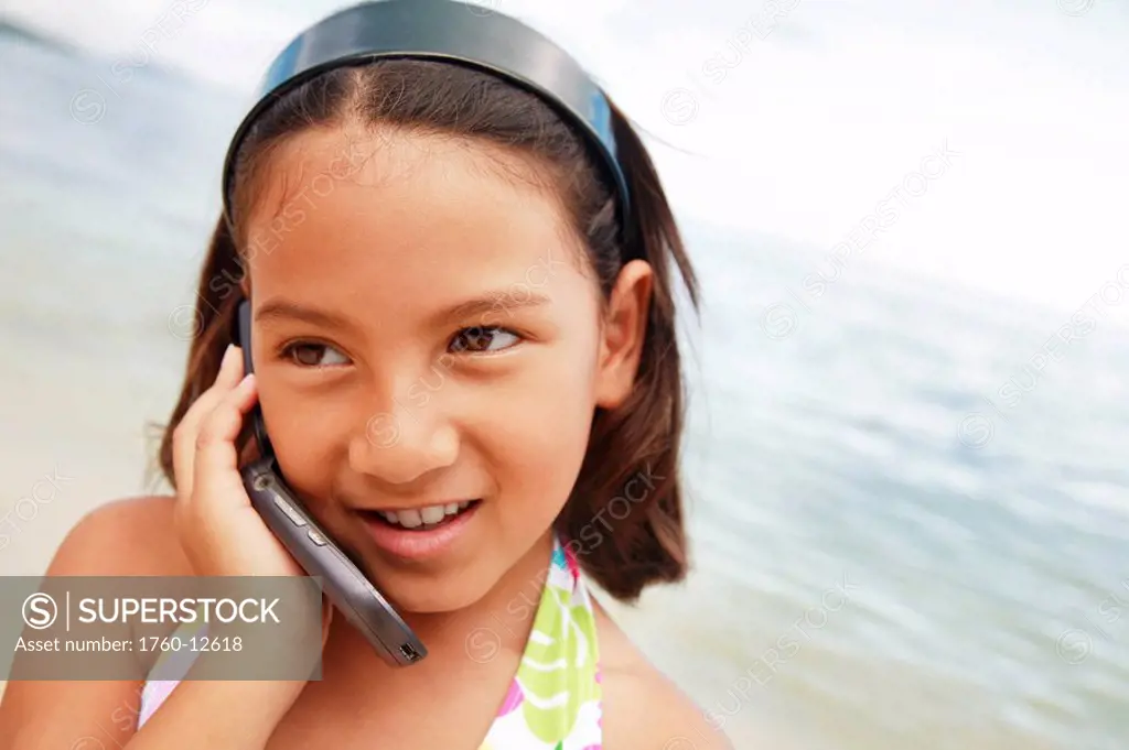 Hawaii, Oahu, Young girl talking on her cell phone at the beach.