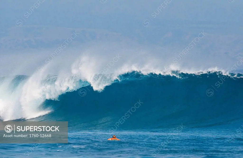 Hawaii, Maui, Kapalua, Surfer paddling out towards large breaking wave