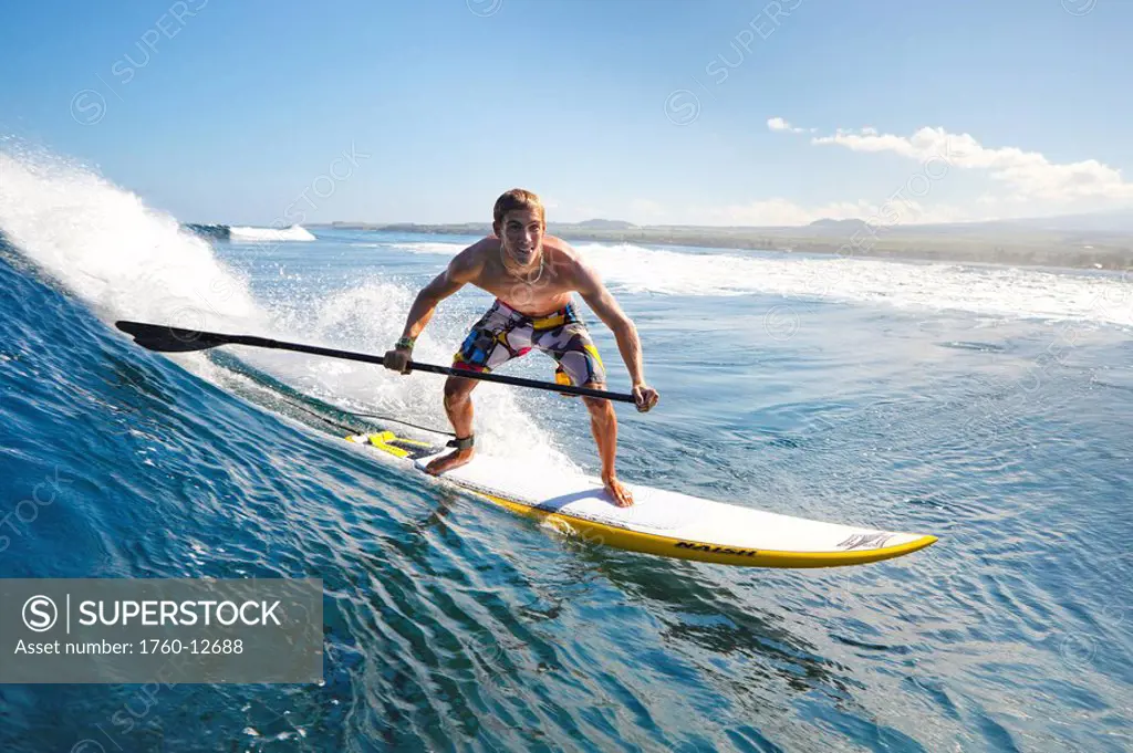 Hawaii, Maui, Paia, Athletic stand up paddle boarder rides wave