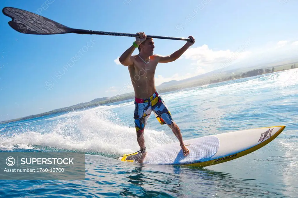 Hawaii, Maui, Paia, Athletic stand up paddle boarder rides wave