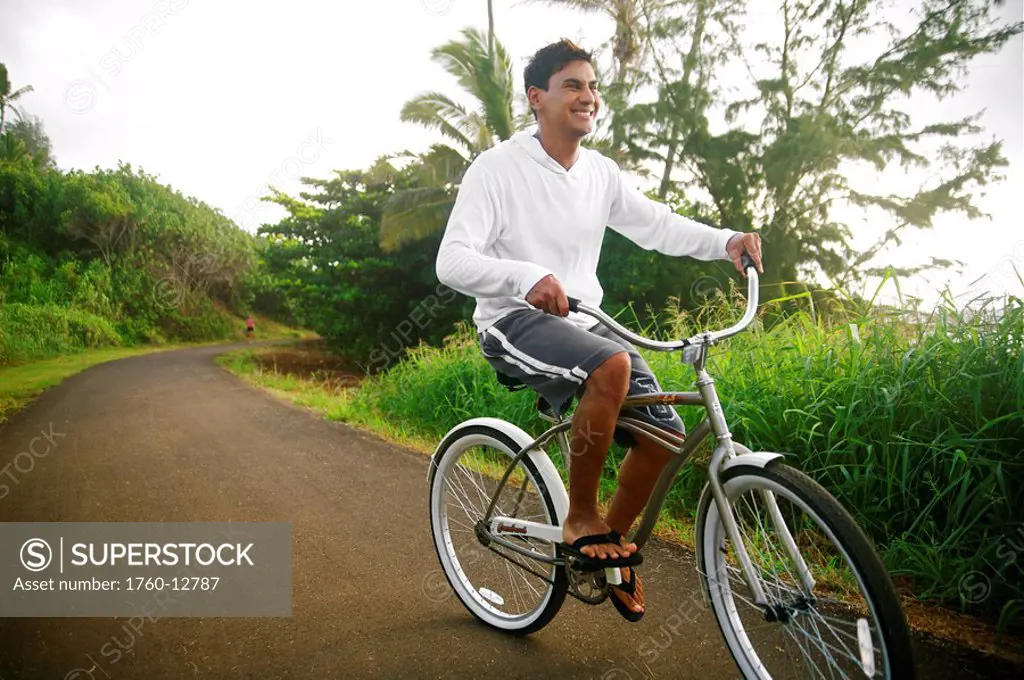 Hawaii, Kauai, Kealia Beach, Young man riding a bike on the bike path.