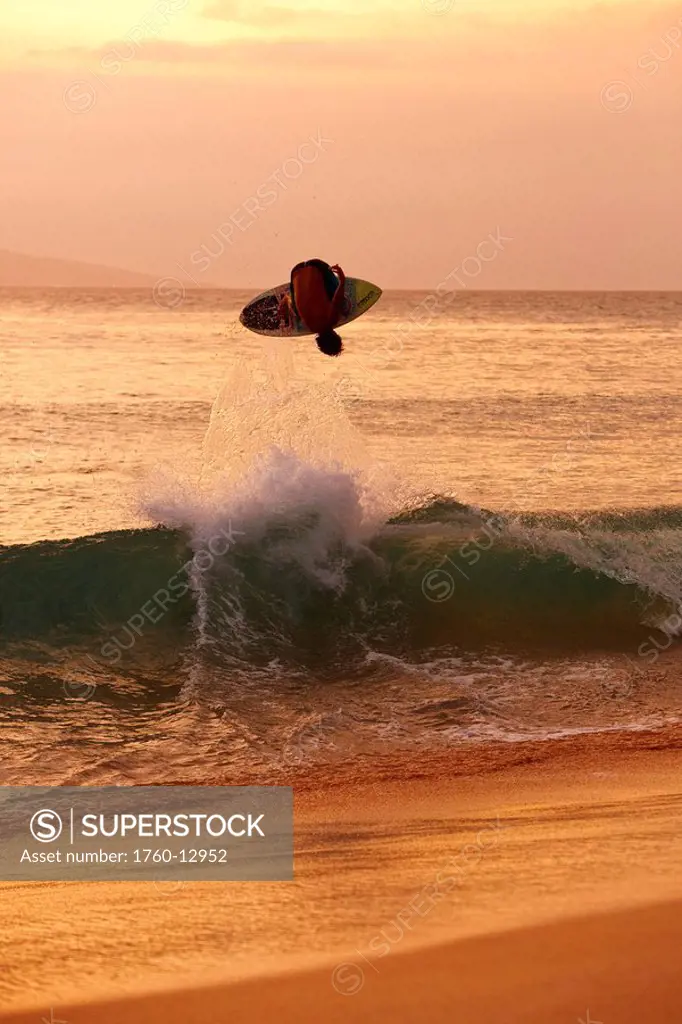 Hawaii, Maui, Makena, Skimboarder gets big air off a wave at sunset