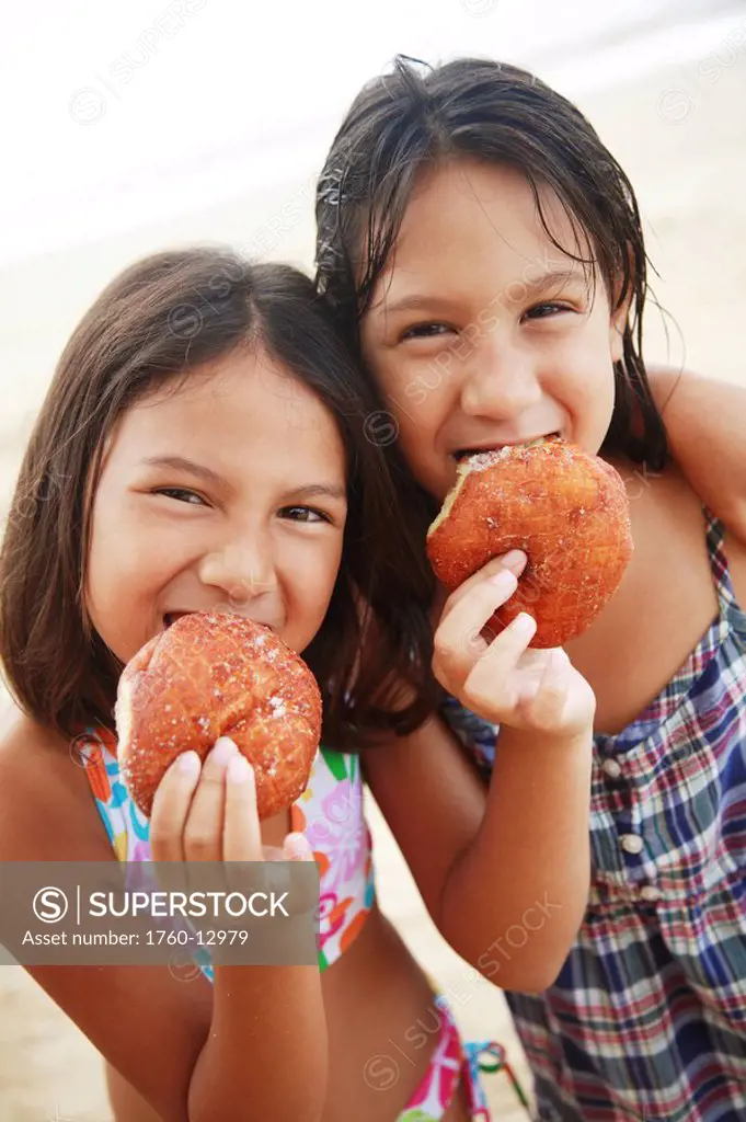 Hawaii, Oahu, Two young girls enjoying yummy malasadas.