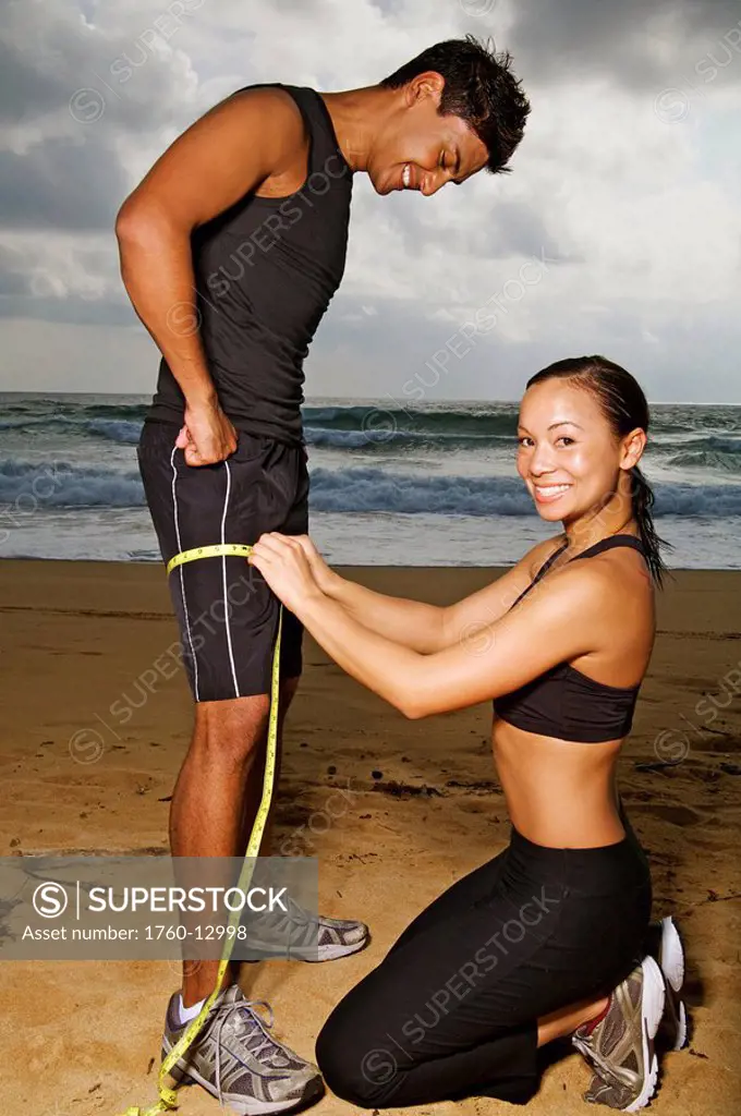 Hawaii, Kauai, Kealia Beach, Young fit couple doing body measurements.