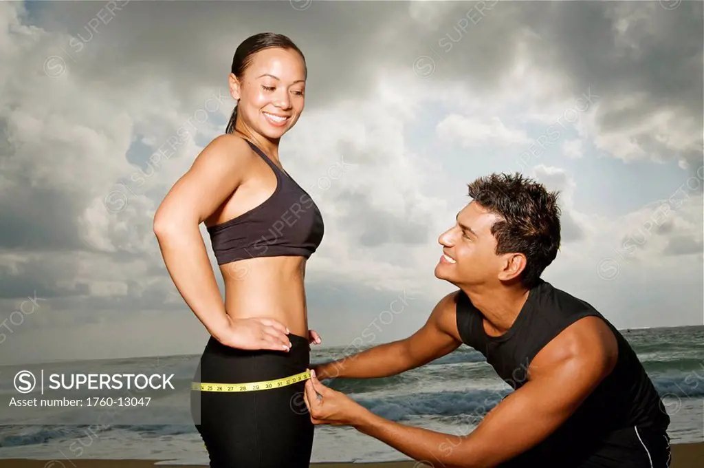 Hawaii, Kauai, Kealia Beach, Young fit couple doing body measurements.