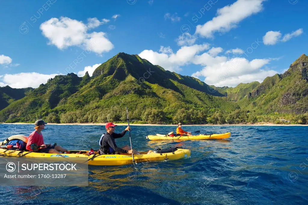 Hawaii, Kauai, Na Pali Coast, Group of kayakers paddling along coastline, Beautiful mountains in background. Editorial Use Only.