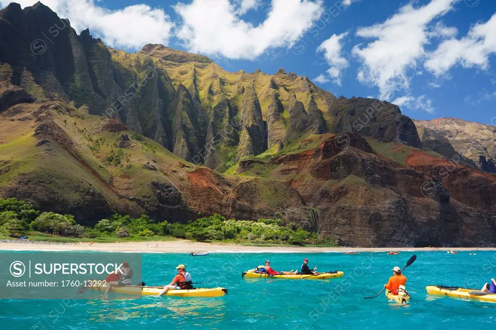 Hawaii, Kauai, Na Pali Coast, Group of kayakers paddling along coastline, Beautiful mountain ridges in background. Editorial Use Only.