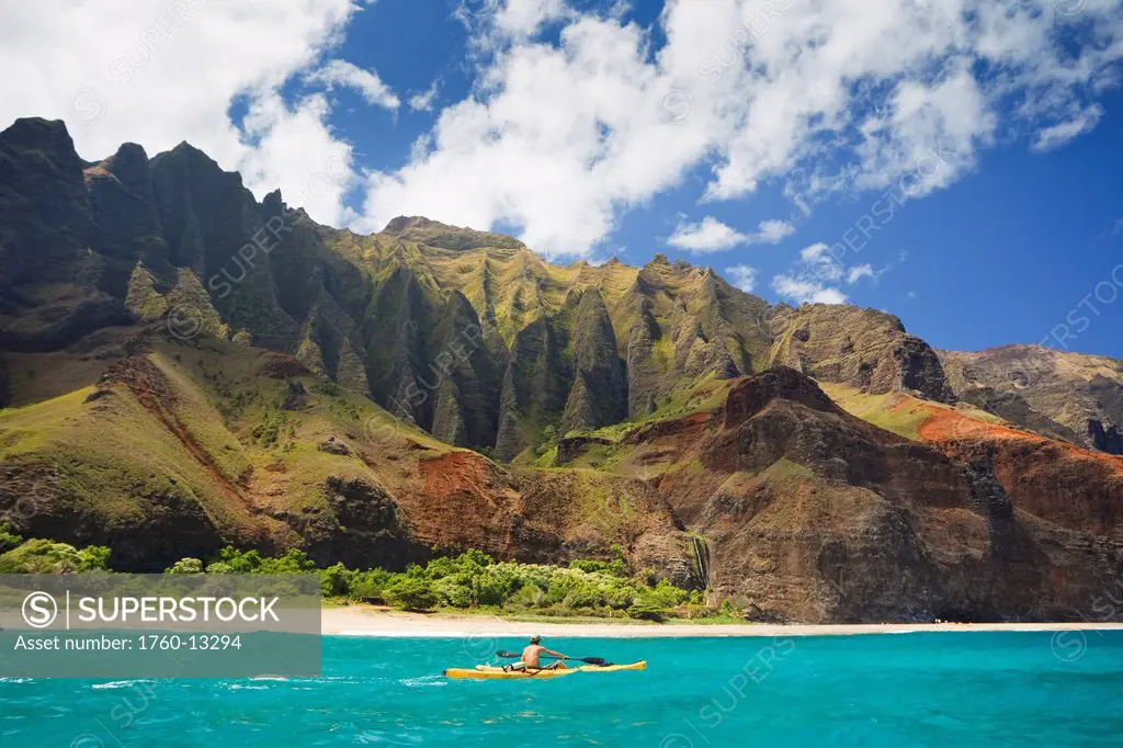 Hawaii, Kauai, Na Pali Coast, Man kayaking along coastline, Beautiful mountain ridges in background. Editorial Use Only.