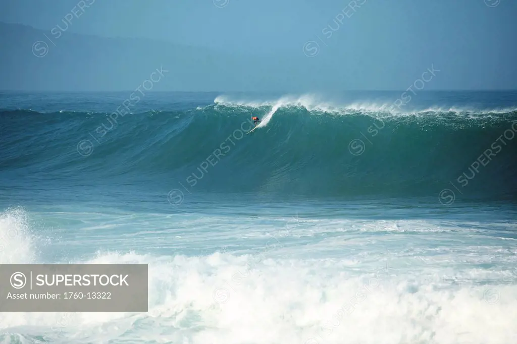 Hawaii, Oahu, North Shore, Waimea Bay, Surfer appears tiny when catching giant wave.