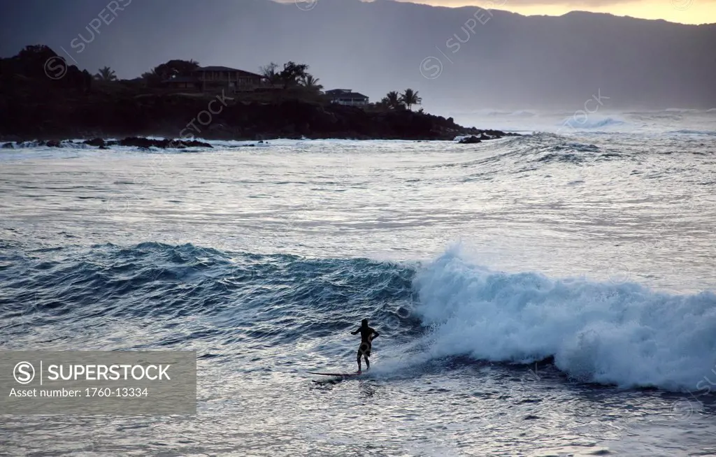 Hawaii, Oahu, North Shore, Waimea Bay, Surfer rides a wave back to shore.