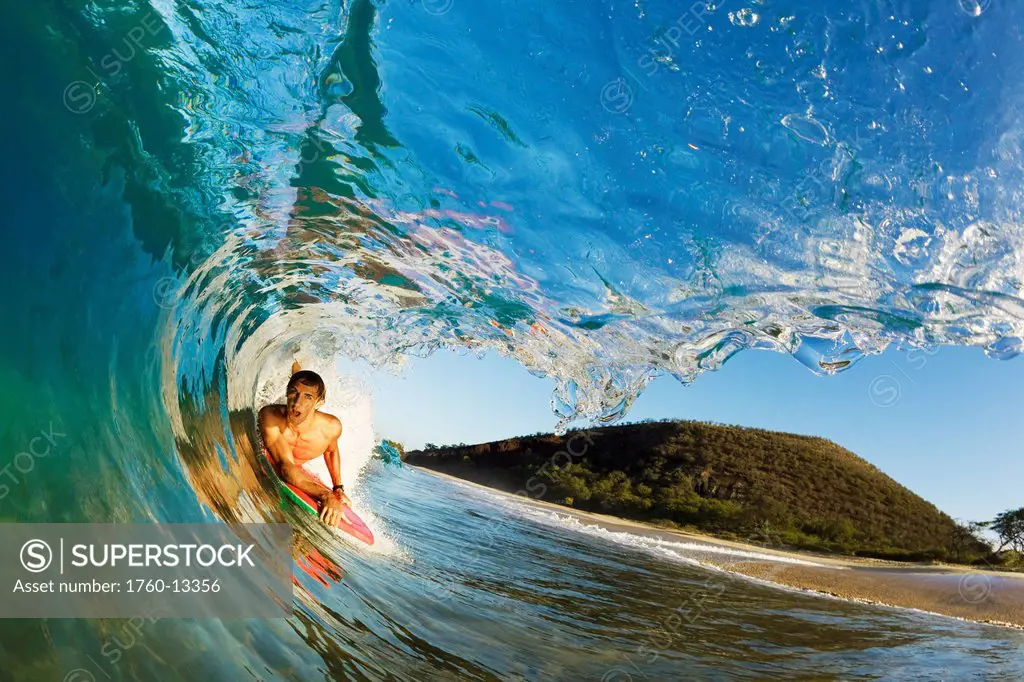 Hawaii, Maui, Makena _ Big Beach, Boogie boarder riding barrel of beautiful wave, Sunrise light.
