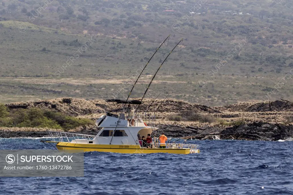 Sportfishing boat with deployed fishing rods trolling off the Kona coast; Kona, Island of Hawaii, Hawaii, United States of America